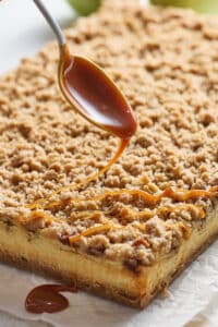 Caramel Apple Cheesecake Bars being drizzled with caramel sauce.